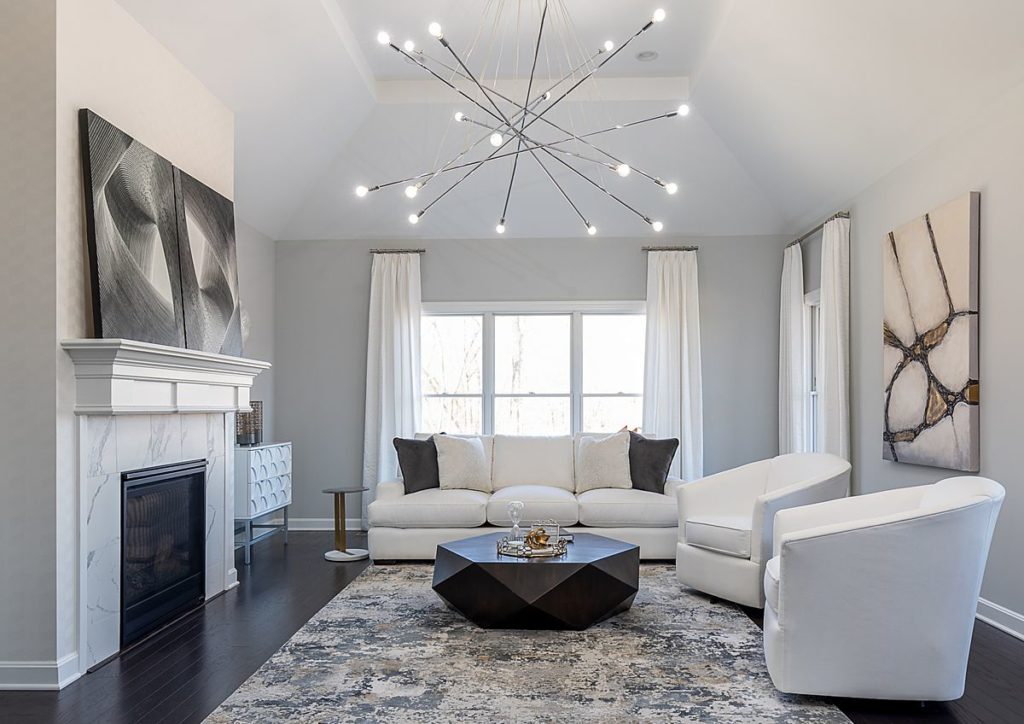 This cool, white contemporary living room is crowned with a giant light fixture.
